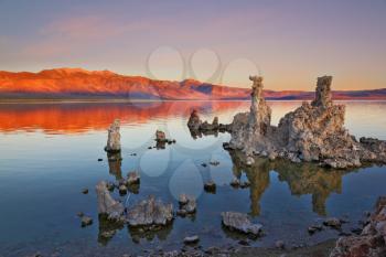 The magic of Mono Lake. Outliers -calcareous tufa formation on the smooth water of the lake. Orange sunset