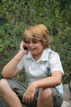 Beautiful ten years' boy with light golden hair talking on a mobile phone