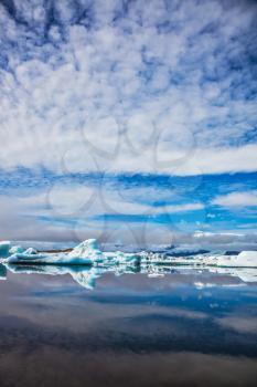 Iceland. Ice magnificence. Floating ice and clouds are reflected in smooth mirror water of the Ice lagoon