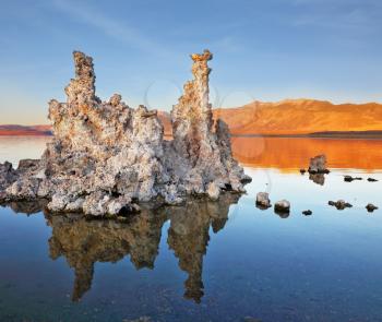 The magic of Mono Lake. Outliers - bizarre limestone formations reflected in the smooth water. Orange sunset