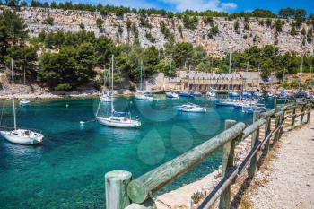 Narrow fjords between stony coast. White sailing yachts wait for the owners.  National Park Calanques on the Mediterranean coast