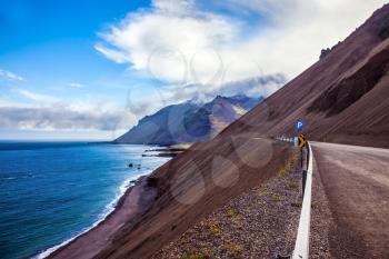 Iceland in July. The road along the Atlantic coast runs along the steep slope of cooled volcanic
