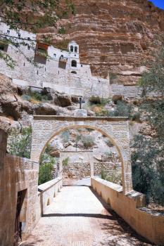 Wadi Kelt near Jerusalem. On the steep wall of the gorge - Monastery of St. George the Victorious. The massive stone gate on the mountain road leading to the temple