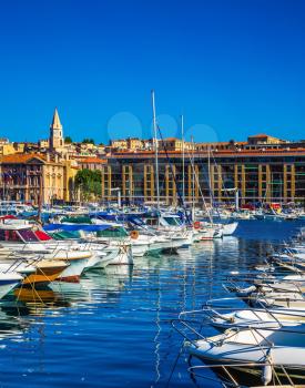 The water area of Marseille Old Port. Rows of sailing yachts, motor boats and fishing boats. The blue water reflects the ancient buildings on the waterfront