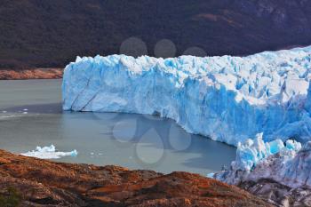 White-blue ice massif multimeter height rises over the lake. Giant lake Perito Moreno glacier