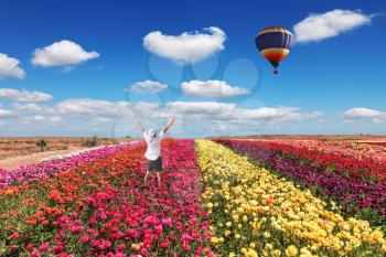 Enthusiastic tourists threw up his hands. Big balloon flies over field of flowering.
