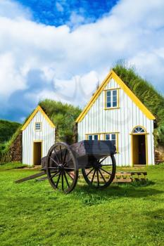 The ancient two-wheeled wooden cart on the front lawn. The village first settlers in Iceland. The recreated village - museum of pioneers - Vikings