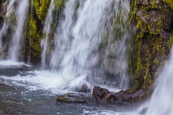  Powerful cascading waterfall on the mossy cliff. Summer day in the cold Iceland
