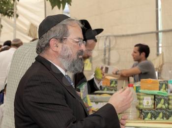 JERUSALEM, ISRAEL - SEPTEMBER 18, 2013: The religious Jew in a black skullcap carefully chooses ritual plant - myrtle for Sukkot.
