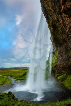 The passage between waterfall and rock. The warm July day in Iceland. Seljalandsfoss waterfall