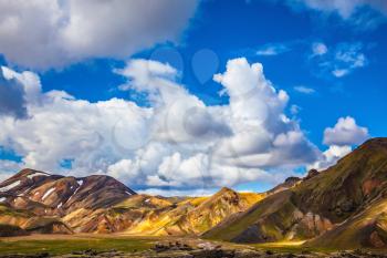 Multi-colored mountains from mineral rhyolite are lit with the July sun. Travel to Iceland in the summer. National park Landmannalaugar