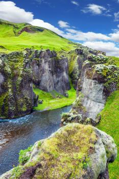  Bizarre shape of cliffs surround the stream with glacial water. The concept of active northern tourism. The striking canyon in Iceland