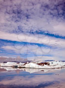 Clouds and ice floes are reflected in the smooth water surface. Morning in the Ice Lagoon. Drift ice Ice Lagoon - Jokulsarlon. The concept of extreme northern tourism