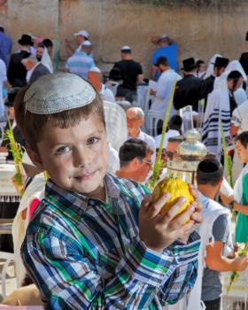  Charming seven year old boy in white festive skullcap with etrog. Sukkot at the Western Wall of Temple in Jerusalem