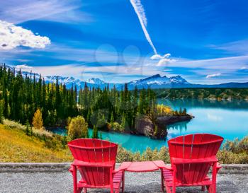 Warm September in the mountains of Canada. Two red comfortable loungers by the Abraham lake with turquoise water. Concept of ecological and active tourism
