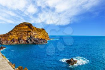 Calm bay with azure water. Rocks and stones off the shores of the volcanic island of Madeira. The concept of ecological and exotic tourism