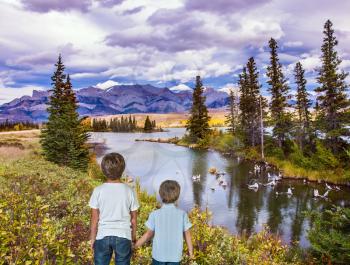 Two lovely boys admire the mountains and lakes. Magnificent landscape in the Rocky Mountains. The concept of ecological and active tourism