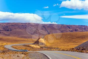 Asphalt road in the Patagonia prairie. Summer day in February. The concept of active and extreme tourism