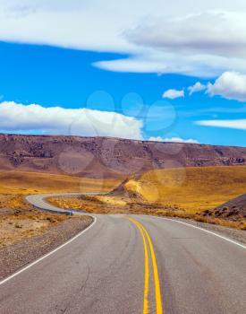 Sharp turn of the road in the Argentine prairie. Patagonia. Summer day in February. The concept of active and extreme tourism