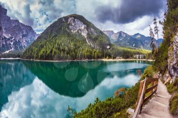 Magnificent Alpine lake Lago di Braies. Walking trail around the lake is fenced with wooden railings. The concept of environmental and hiking