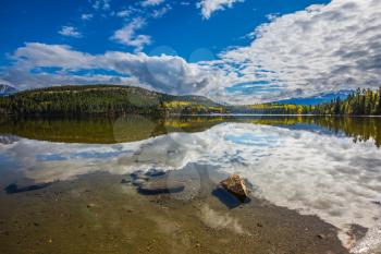  Pyramid Mountain and white clouds reflected in the smooth water of Pyramid Lake. Sunny morning in the Rocky Mountains, Canada