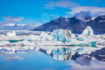 Ice lagoon in Iceland. Ocean Bay is surrounded by volcanic mountains and glaciers. Icebergs and ice floes are reflected in the mirrored water