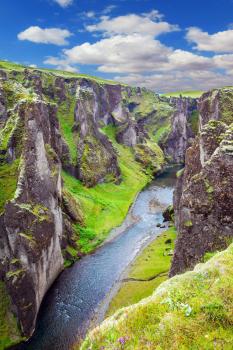  Steep vertical cliffs surround the stream of very cold water. Fantastic canyon in Iceland - Fyadrarglyufur. The concept of active northern tourism