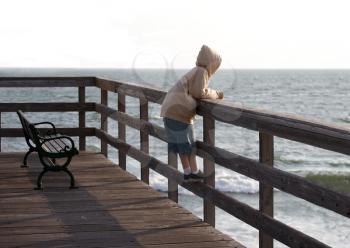 Royalty Free Photo of a Child Alone on a Boardwalk Railing