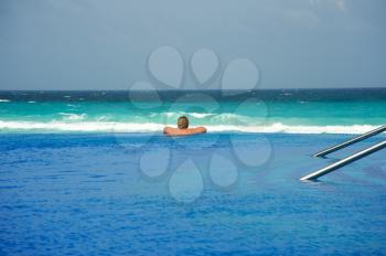 Woman relaxing at infinity pool