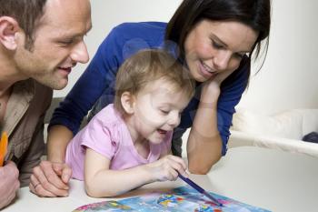 Royalty Free Photo of a Couple Helping Their Daughter With an Activity Book