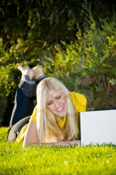 Royalty Free Photo of a Woman Lying in the Grass With a Laptop