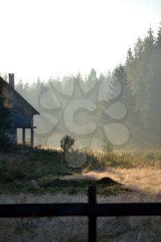 Foggy landscape with cottage in the mountains at the summer morning