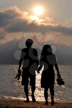 Romantic lovers walking on the beach at sunrise, 