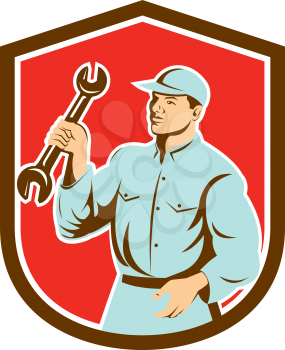 Illustration of a mechanic holding spanner wrench looking to the side set inside shield crest on isolated background done in retro style. 