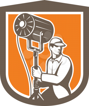 Illustration of a electrical lighting technician crew with fresnel spotlight looking to side set inside shield crest shape on isolated background done in retro style.
