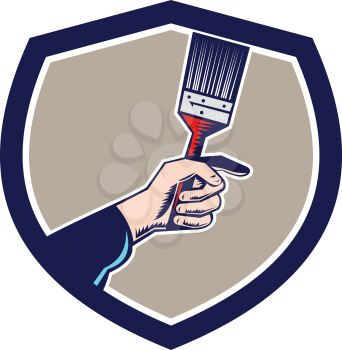Illustration of a painter hand holding paintbrush set inside shield crest on isolated background done in retro style. 