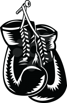 Retro woodcut style illustration of a pair of boxing gloves hanging on nail on isolated background done in black and white.