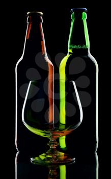 Two bottles of beer and glass, isolated on a black background.