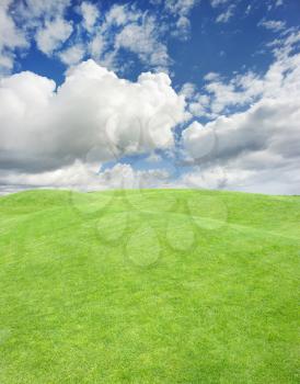 Hill covered with smooth green grass against the sky
