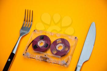 Royalty Free Photo of an Audio Tape Between a Fork and Knife