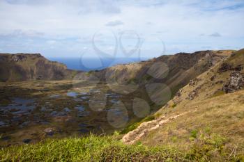 Dramatic Volcano crater near Orongo vilage, Easter Island, grassy walls, sharp rocks, endless ocean