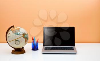 Royalty Free Photo of a Desk With a Computer Pens and Globe