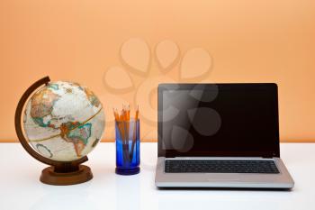 Royalty Free Photo of a Desk With a Globe Laptop and Pens