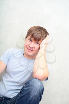 relaxed man sitting on the floor against wall