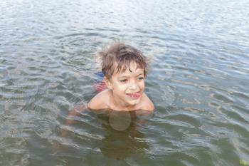 Cute little boy playing in water outdoors on summer day
