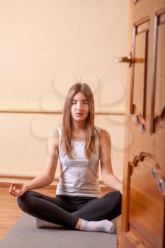 Pretty blonde women meditating in yoga studio on beige background through the open door . Mental health spiritual development concept
