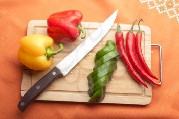 Red peppers on wood with knife (chilli sliced)