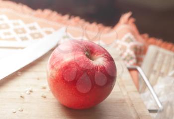 Red apple on a wooden plate with knife