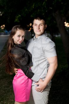 Young couple in love. Young loving couple, young woman embracing his boyfriend. Hand in hand. Side view