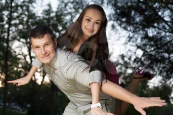 Young loving couple piggybacking in the park in the sunset closeup